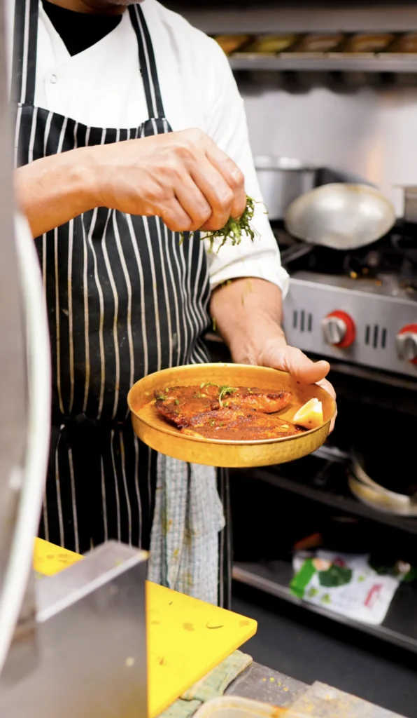 Chef plating a dish in the Dawat Bar and Kitchen kitchen