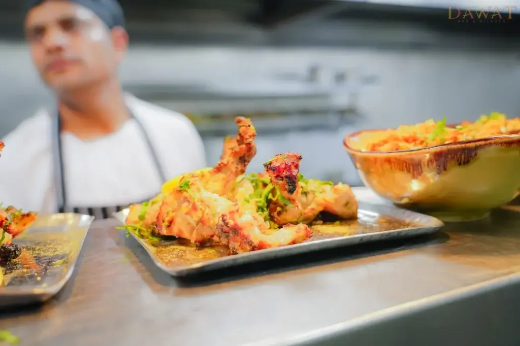 Chef presenting a tandoori dish at Dawat Bar and Kitchen