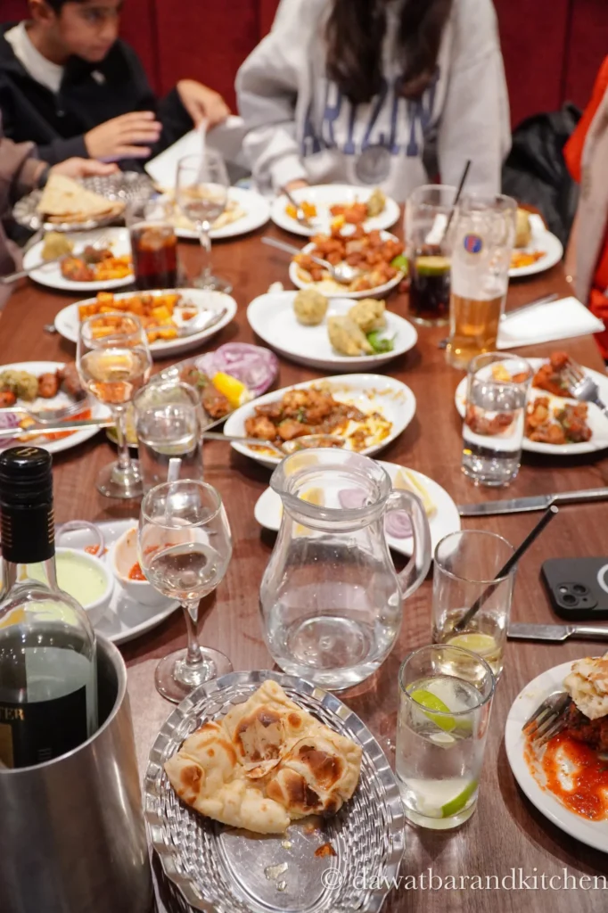 Group table filled with Indian dishes, naan and drinks at Dawat