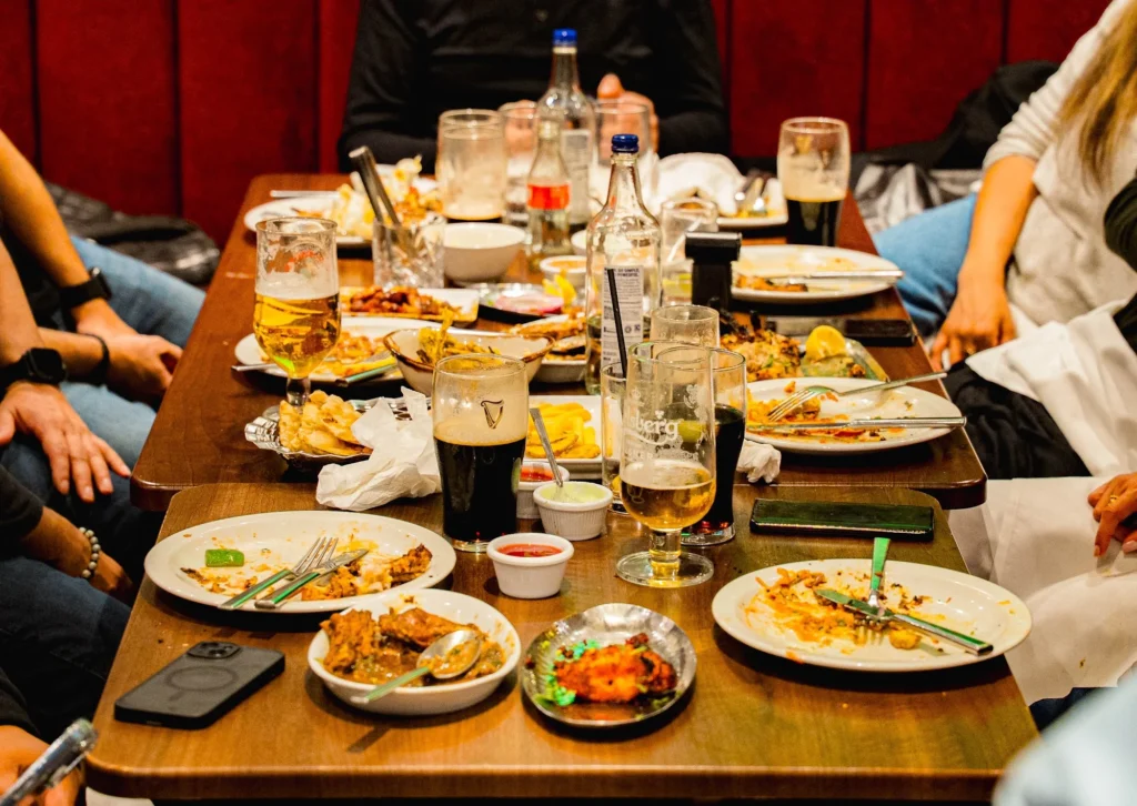 Group dinner on a long table at Dawat Bar and Kitchen, shared plates and drinks