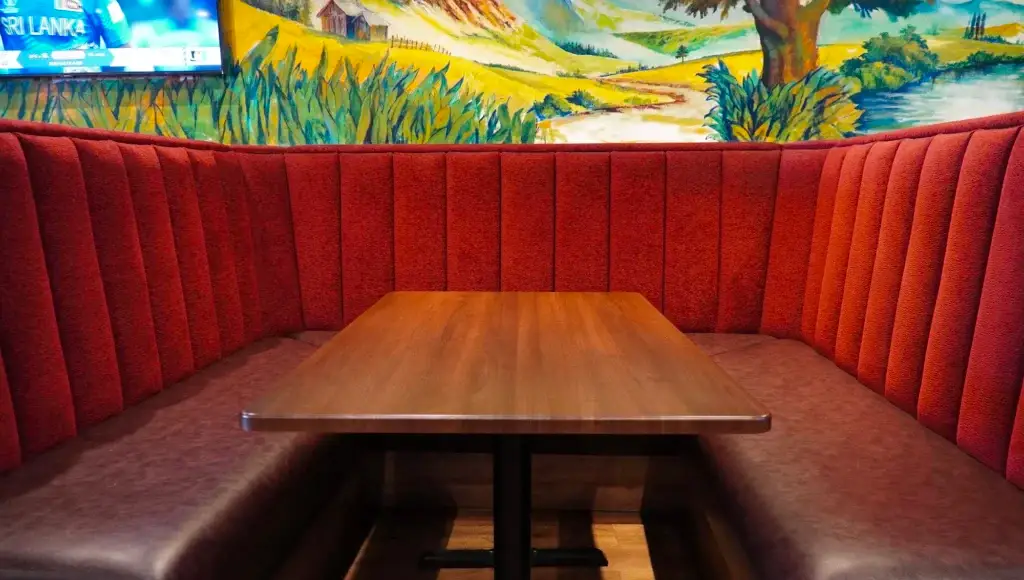 Red booth seating under the mural at Dawat Bar and Kitchen