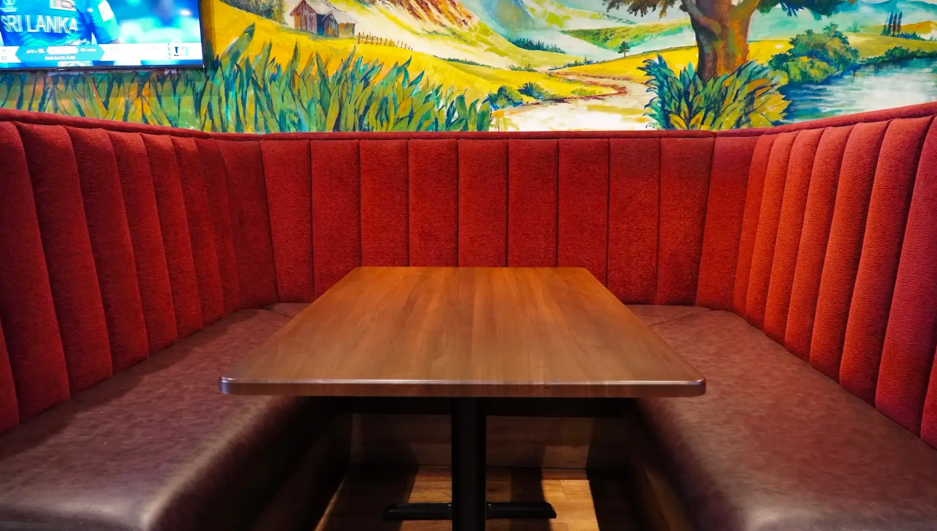 Red booth seating under the mural at Dawat Bar and Kitchen