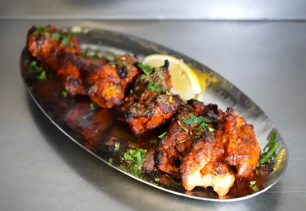 Tandoori chicken wings with lemon on a steel platter at Dawat Bar and Kitchen