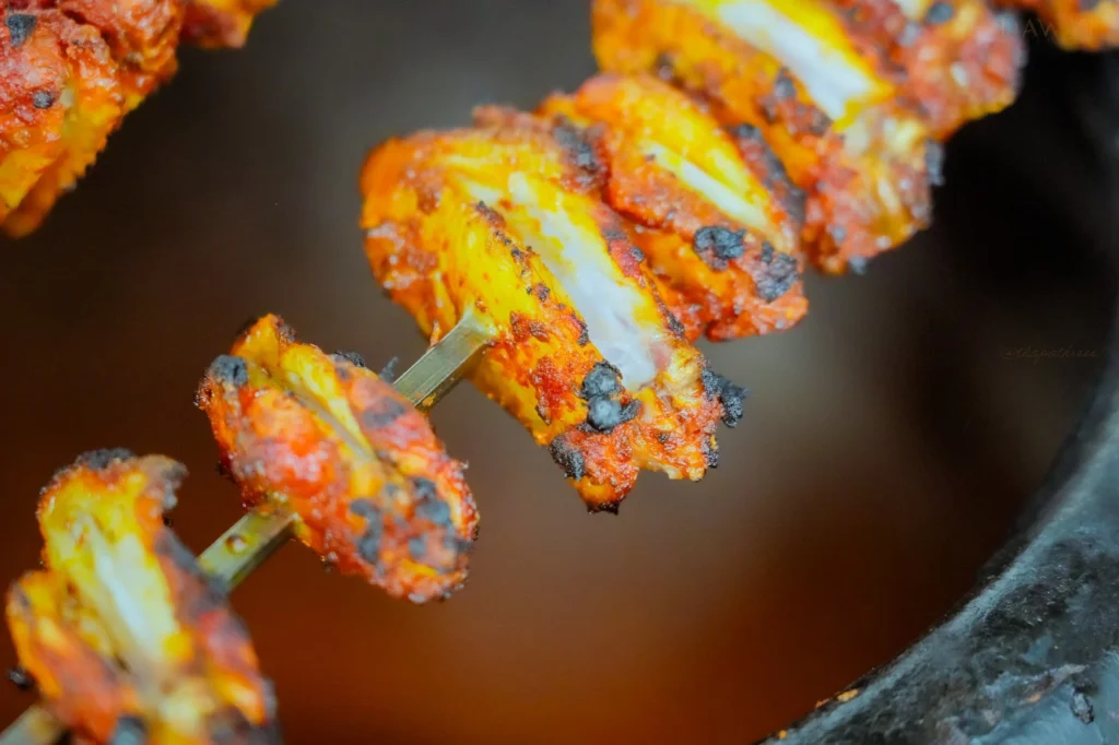 Tandoori chicken wings on a skewer in the tandoor at Dawat Bar and Kitchen